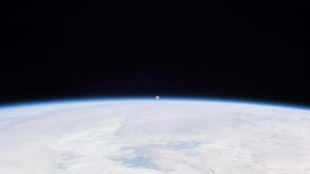 The Moon can be seen in the distance with the Earth in the foreground.